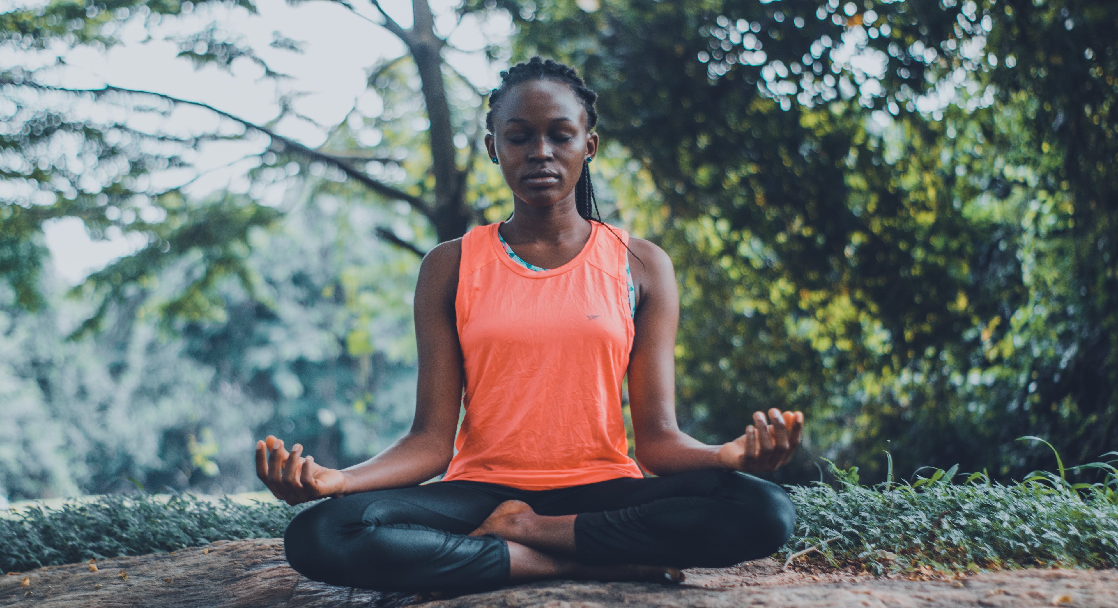 young woman with eyes closed, practicing trauma release yoga outdoors