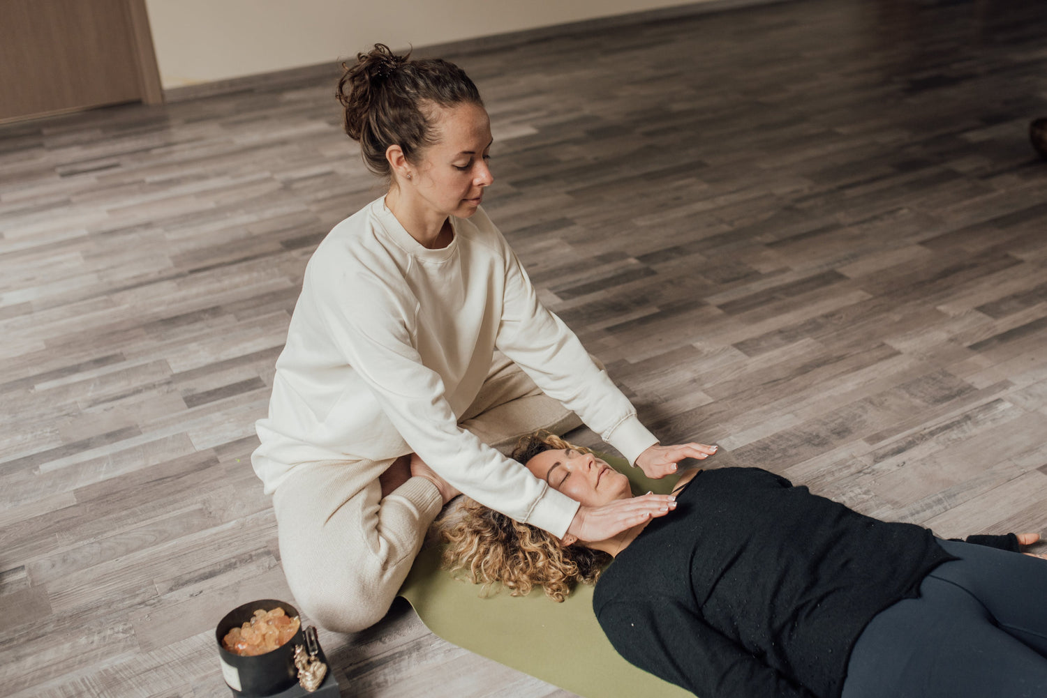 a Reiki healer practicing energy healing for trauma on a woman laying on the floor